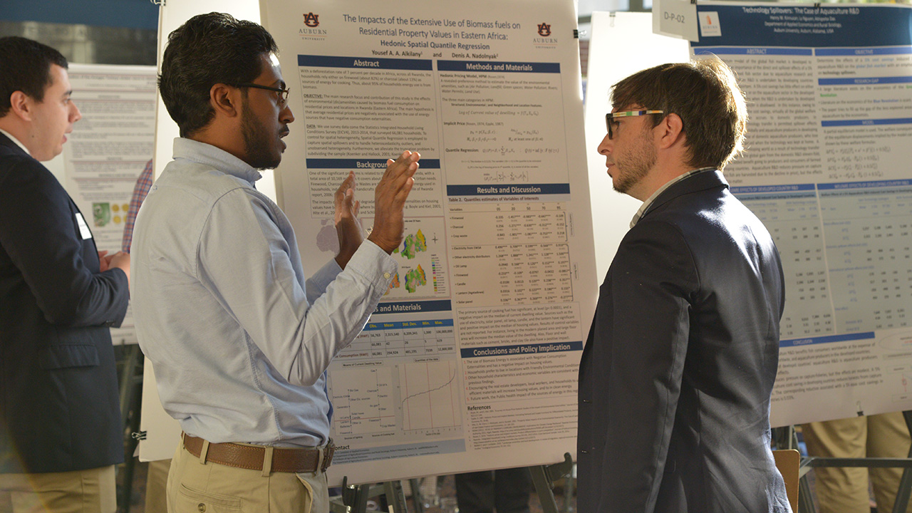 Graduate student tells professor about the research poster in front of them