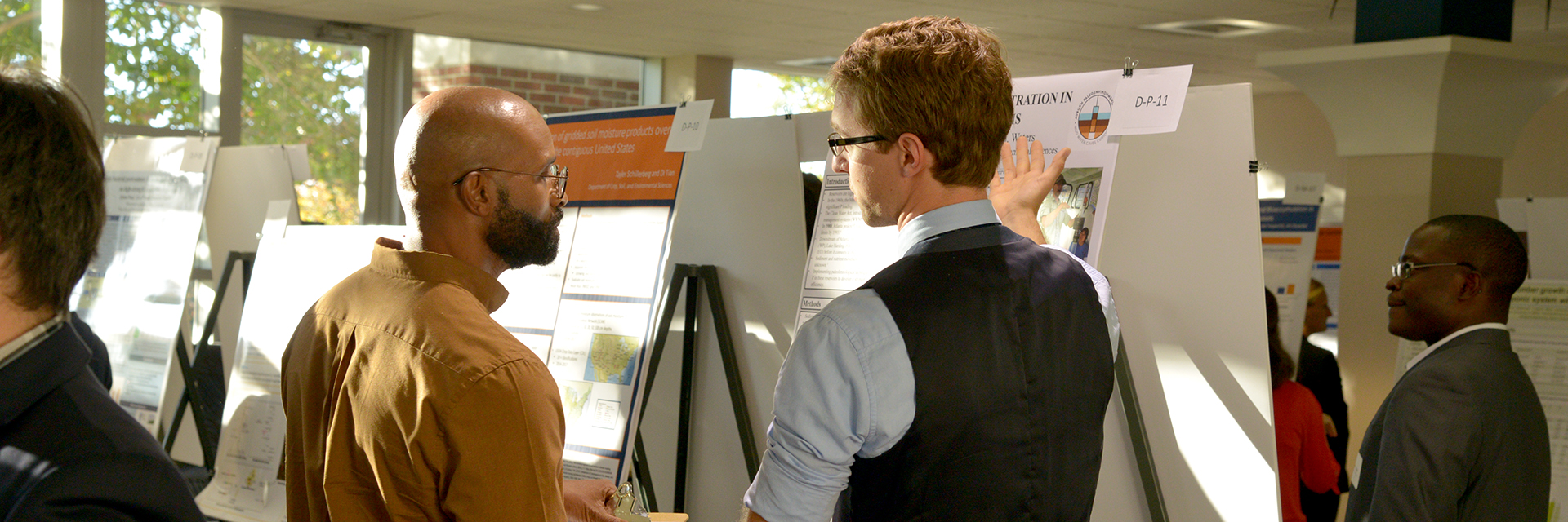 Graduate-Student-in-vest-suit-presents-his-Research-Poster-Showcase-Auburn-University-College-of-Agriculture-Alumni-Center-AL-sm